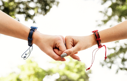 Two female friends doing fist bump outside in summer day