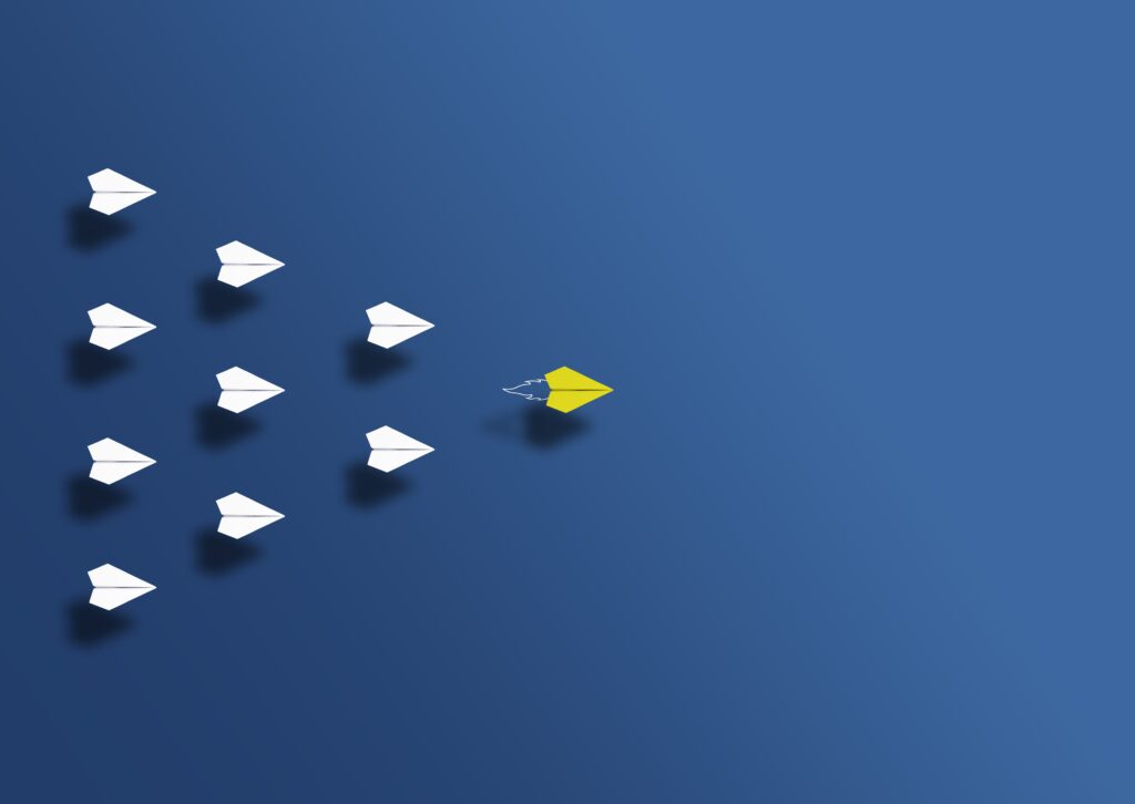 paper planes with a yellow one leading