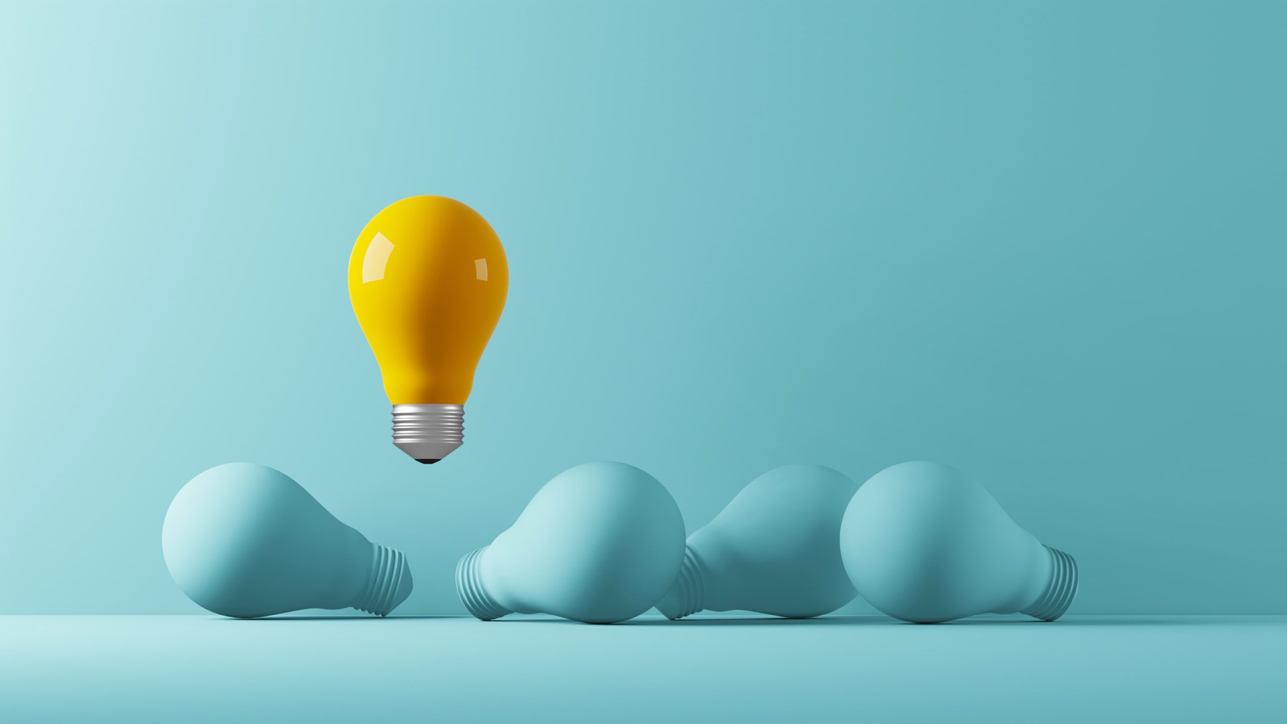 A single yellow lightbulb standing upright among several blue lightbulbs lying down, symbolizing innovation or standing out from the crowd