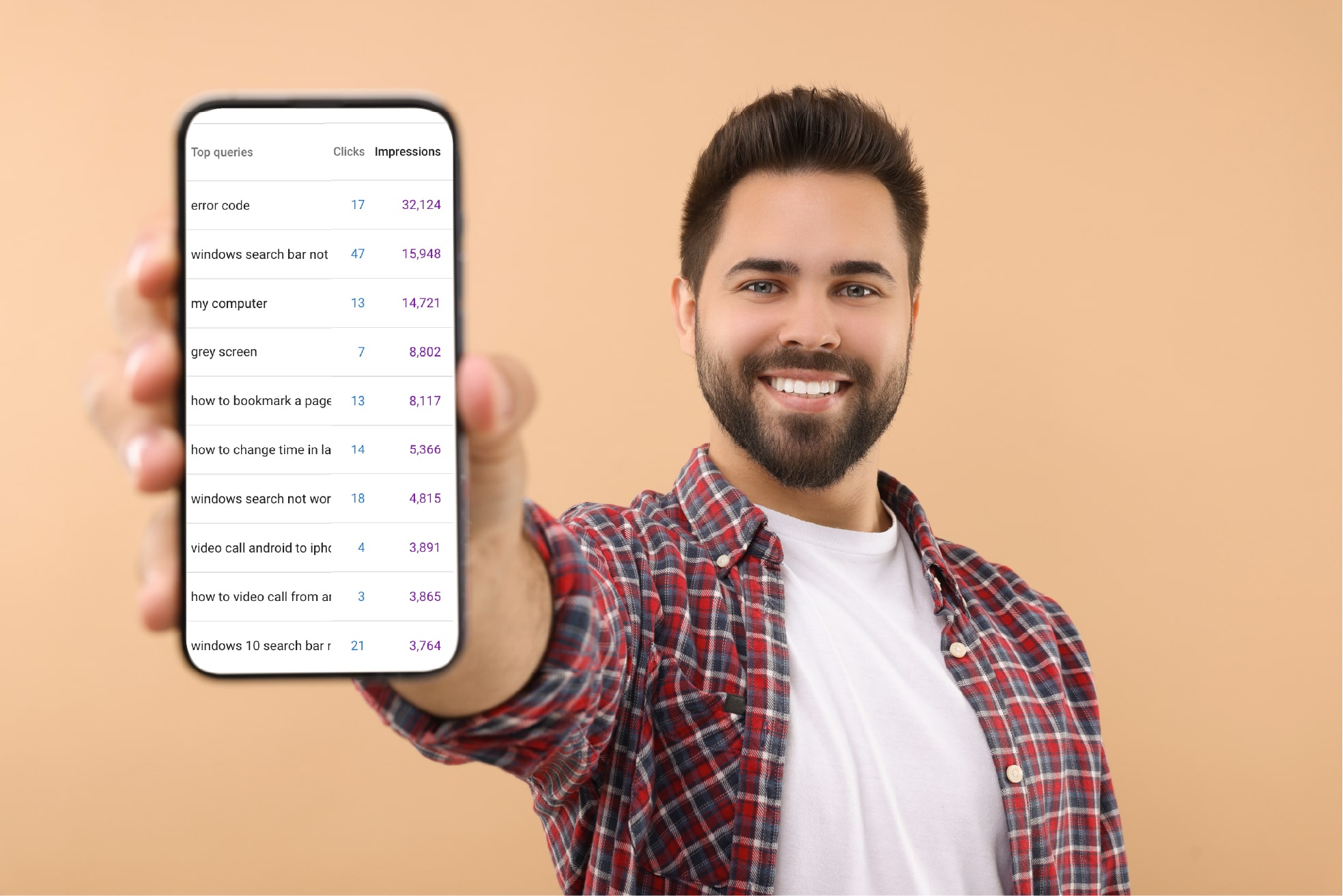 Man in plaid shirt posing in front of orange background. He is holding up a phone with search queries from Google Search Console displayed on screen.