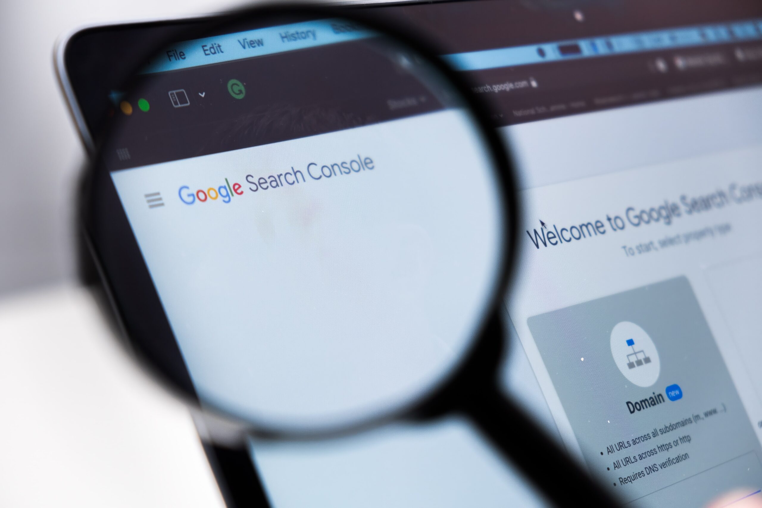 A magnifying glass is held over a computer screen displaying the Google Search Console web page, highlighting the Google Search Console Update and part of the interface—an essential tool for refining your SEO strategy.
