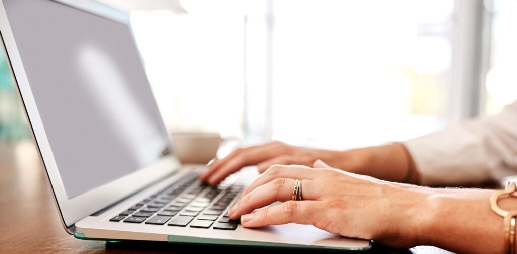 google-search-console-september-2025 Close-up of a person typing on a laptop at a wooden table, with natural light streaming in—a perfect setting for refining an SEO strategy ahead of the September 2025 Google Search Console Update. The individual is wearing a ring and a bracelet.